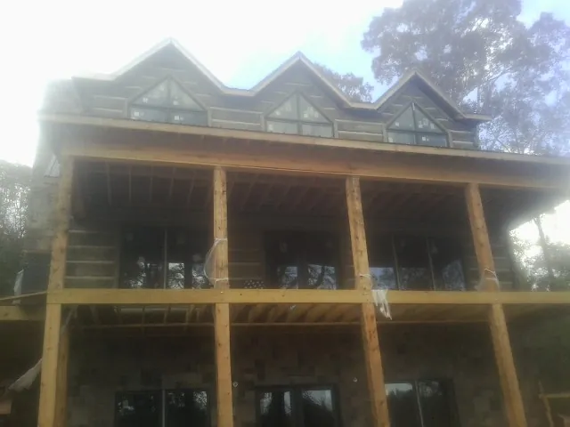 Dormers and porch framing on a large log home under construction — Roof Coating work by our crew in Evansville