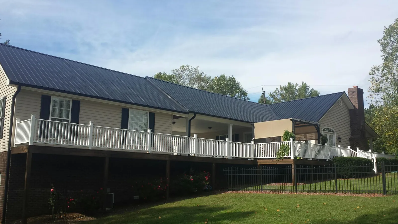 Black metal roof above a long white railed deck on a hillside home in Evansville