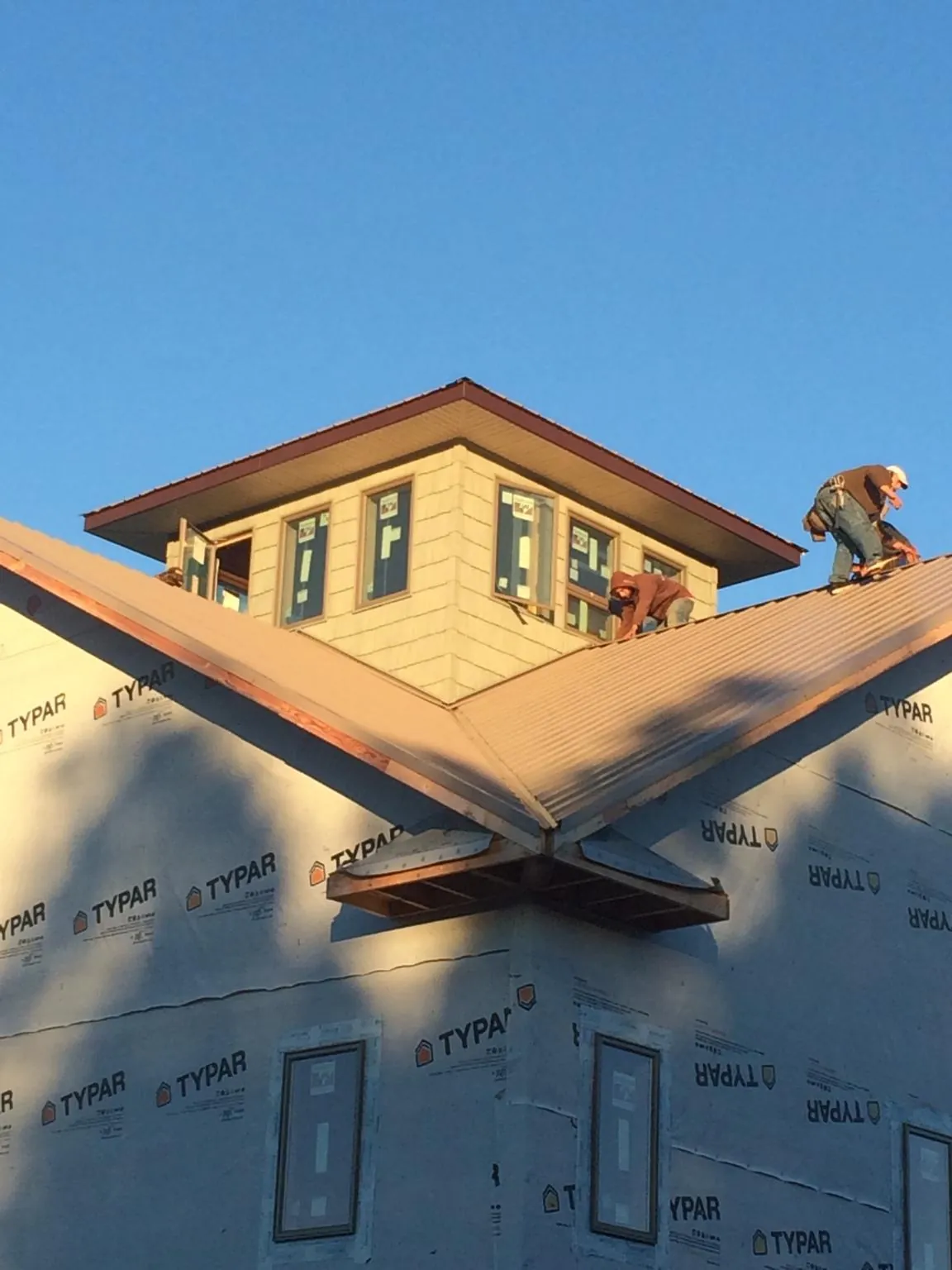 Roofers working around a rooftop cupola on a new metal roof at sunset — Roof Waterproofing in Evansville by Roofing Brothers